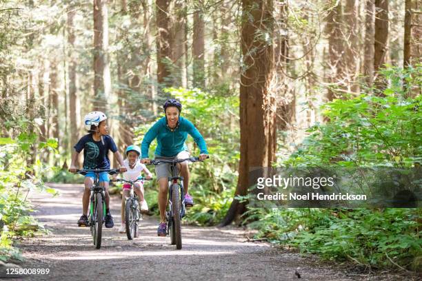 mom and kids race on bikes - bicycle trail outdoor sports stock-fotos und bilder