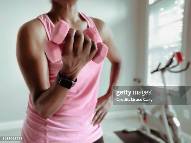 woman tones biceps with lightweight dumbbells - tyngdlyftning bildbanksfoton och bilder