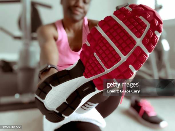 woman sits on floor to put on sports shoes - sole of shoe stock-fotos und bilder