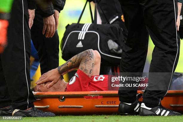 Manchester United's Brazilian midfielder Antony reacts as he is taken off on a stretcher after picking up an injury during the English Premier League...