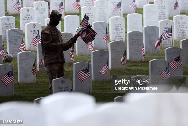 Members of the 3rd U.S. Infantry Regiment place flags at the headstones of U.S. Military personnel buried at Arlington National Cemetery, in...