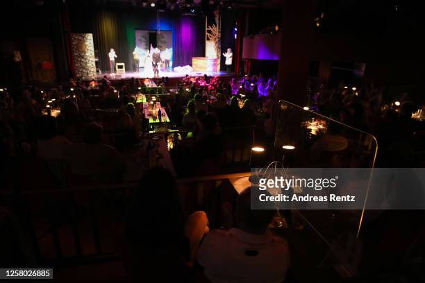 Guests sit separated from each other by a protective spit panel at a table during the theatre play "Beethovens verschollenes Werk" at GOP Varieté...