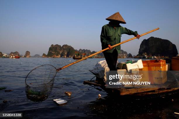 This photo taken on May 17 shows a worker picking up trash from Ha Long Bay in northeast Vietnam. More than seven million visitors came to visit the...
