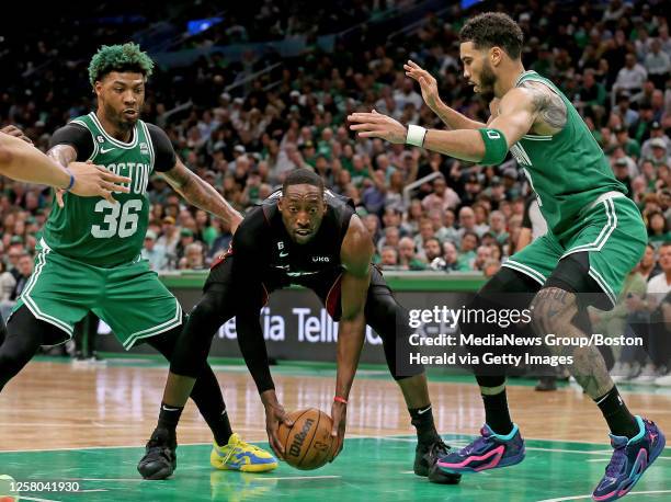 Bam Adebayo of the Miami Heat holds the ball as Marcus Smart and Jayson Tatum of the Boston Celtics move in during the second quarter of the NBA...