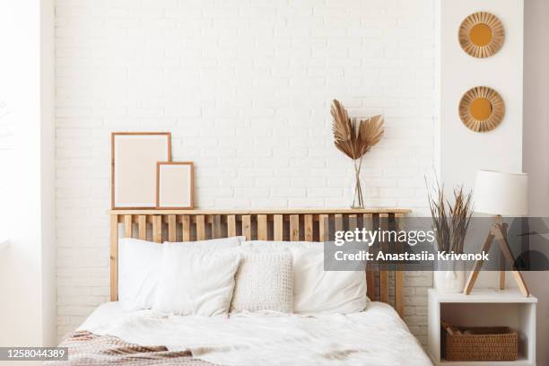 wooden headboard with dry gold palm leaves in a glass vase and two photo frames on it. stylish trendy decoration with copy space. - piezas fotografías e imágenes de stock