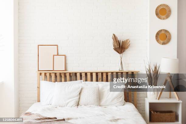 wooden headboard with dry gold palm leaves in a glass vase and two photo frames on it. stylish trendy decoration with copy space. - bedroom interior bildbanksfoton och bilder
