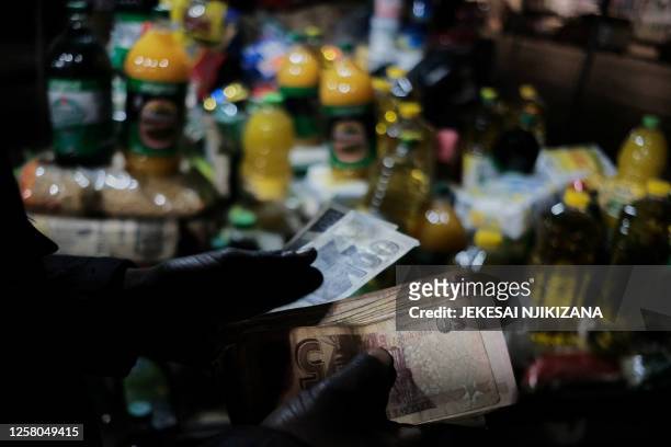 Vendor takes a tally of the out of favour Zimbabwe bond notes at his informal mobile pop-up shop selling basic groceries along Robert Mugabe Road in...