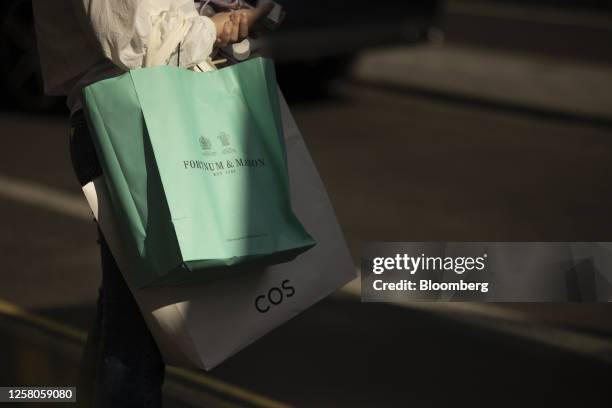 Shopper carries Fortnum and Mason Plc and Cos bags in central London, UK, on Thursday, May 25, 2023. UK retailers saw sales jump more than expected...