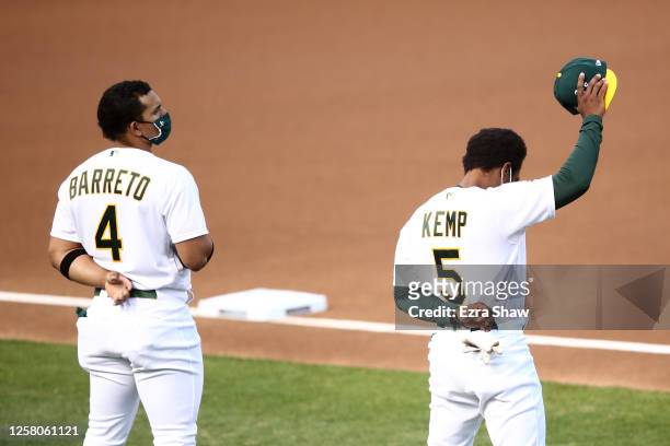 Tony Kemp of the Oakland Athletics raises his hand while standing next to Franklin Barreto during the National Anthem before their opening day game...