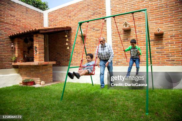 grandpa swinging children in the yard of the house - estado do méxico imagens e fotografias de stock