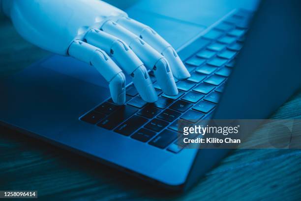 robotic hand using laptop (concept of ai replacing white collar worker) - typing stock pictures, royalty-free photos & images