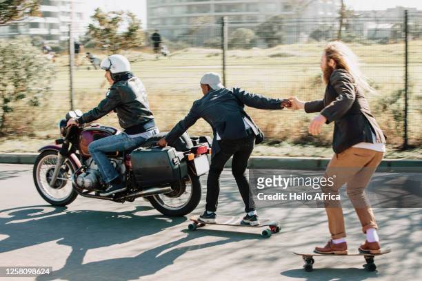 motorcyclist towing two skaters - off beat stock pictures, royalty-free photos & images