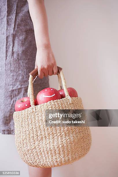 a woman with a basket containing apple. - frau apfel stock-fotos und bilder