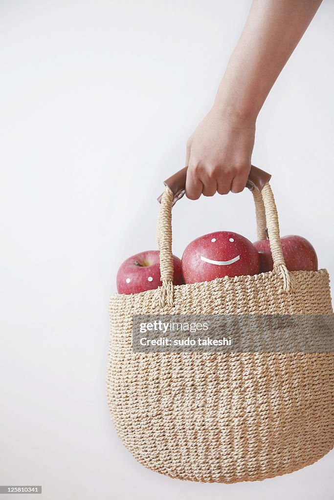 A woman with a basket containing apple