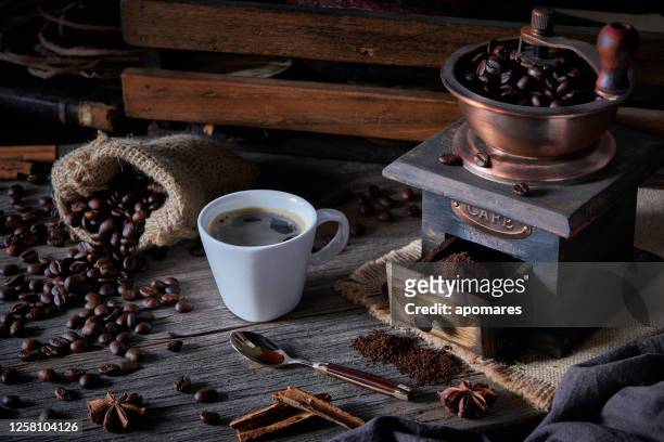 咖啡杯和研磨機在老式桌子上和烤咖啡豆在粗麻布。 - coffee grinder 個照片及圖片檔
