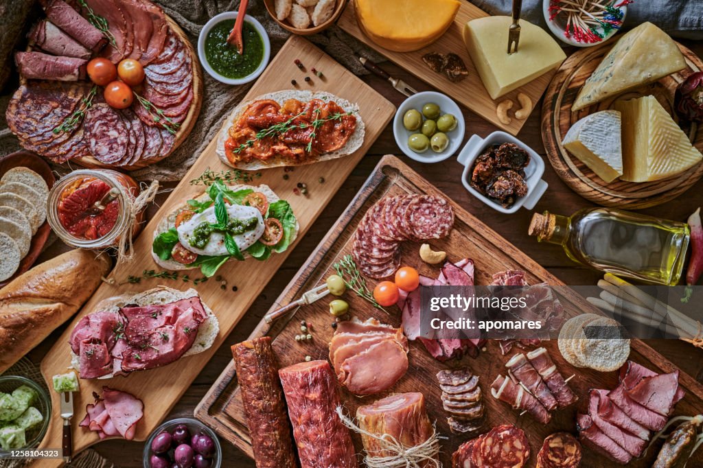 Tapas of cheese, cured ham, salami wine and chorizo on a rustic wooden table