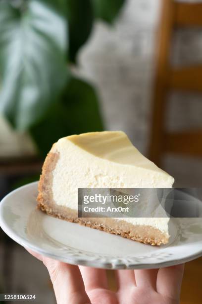 slice of cheesecak on plate in hands - cheesecake white stockfoto's en -beelden