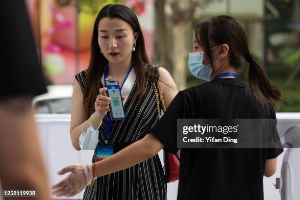 Staff worker wears a protective masks while checking an audience's healthy QR code by the entrance prior to an outdoor screening event on July 25,...