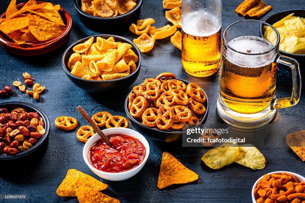 Aperitivos salados y cerveza sobre fondo de pizarra oscura