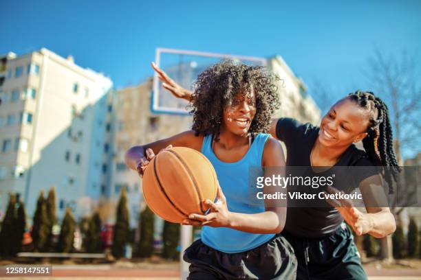 vrouw die basketbal op de speelplaats speelt - women's basketball stockfoto's en -beelden