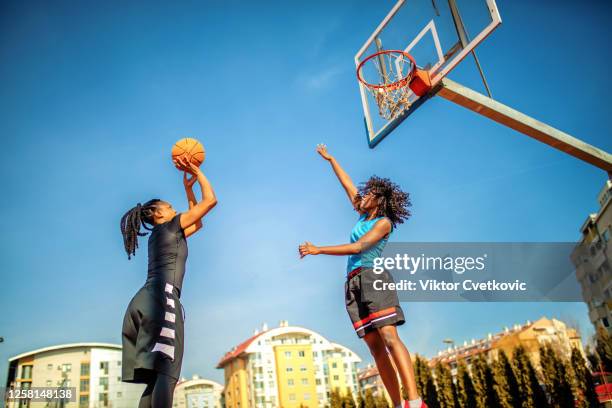 woman playing basketball on the playground - jump shot basketball stock pictures, royalty-free photos & images