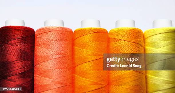 set of spools of red, yellow and orange threads front view close-up macro on white background - orange silk background stock-fotos und bilder