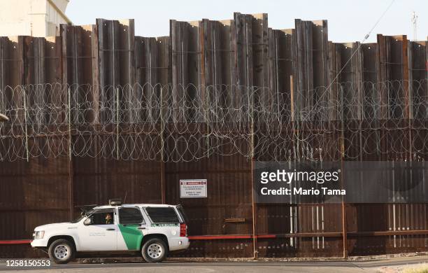 Border Patrol agent is posted in front of the U.S.-Mexico border barrier in Imperial County, which has been hard-hit by the COVID-19 pandemic, on...