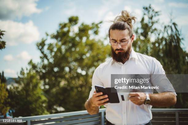 portret van een jonge zakenman die een koffieonderbreking heeft - jonge zakenman met lang haar - de onderbreking van de koffie op het terras van het bureaugebouw - long beard stockfoto's en -beelden