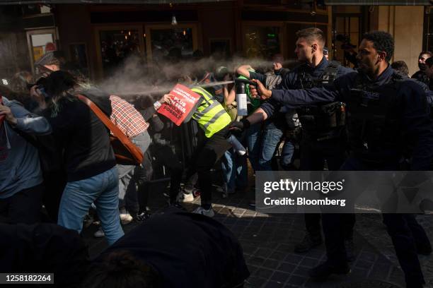 Police officers dispense tear gas to disperse climate activists during a protest outside the TotalEnergies SE annual general meeting venue in Paris,...