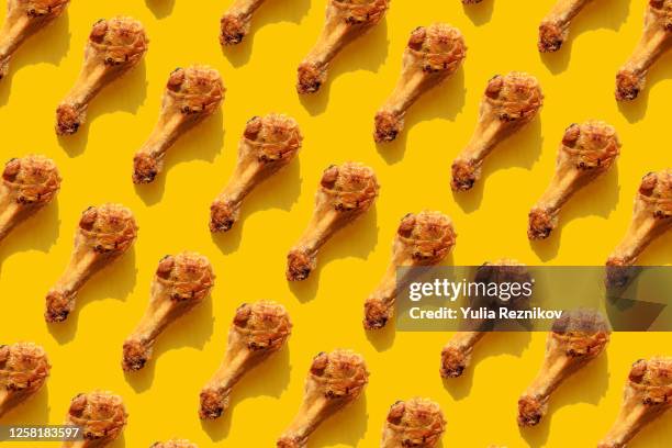 repeated fried chicken legs on the yellow background - hühnchenunterschenkel stock-fotos und bilder