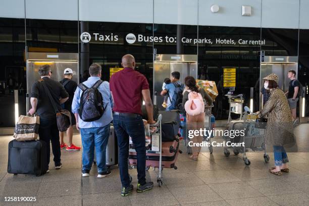 People queue for a lift at Heathrow Airport on May 26, 2023 in London, England. British Airways was forced to cancel dozens of flights after IT...