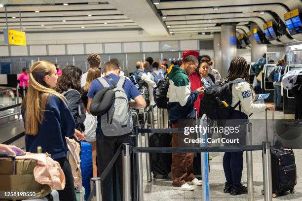 People queue to check in at Heathrow Airport on May 26, 2023 in London, England. British Airways was forced to cancel dozens of flights after IT...