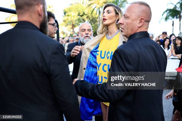 Ukrainian model Alina Baikova , wearing a t-shirt bearing the colours of the Ukrainian flag, talks with security as she arrives for the screening of...