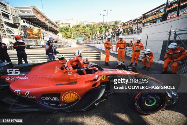 Race marshal poses for photos with the car of Ferrari's Spanish driver Carlos Sainz Jr on the sidelines of a practice session of the Formula One...