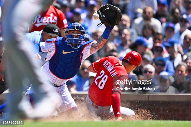 Kevin Newman of the Cincinnati Reds slides home for a run in the fourth inning as catcher Tucker Barnhart of the Chicago Cubs takes the throw at...