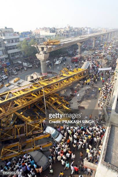 People gather at the site where a crane working on the construction of bridge for the Delhi Metro collasped in New Delhi on October 19, 2008. At...