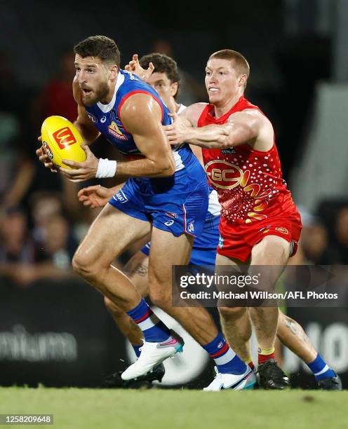 Marcus Bontempelli of the Bulldogs is tackled by Matt Rowell of the Suns during the 2023 AFL Round 11 match between the Gold Coast Suns and the...