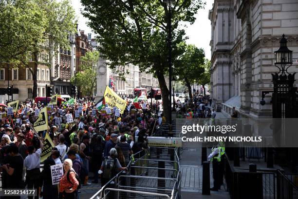 People from different campaign groups hold placards as they march past the entrance gate of Downing Street, in central London, on May 27, 2023 for...