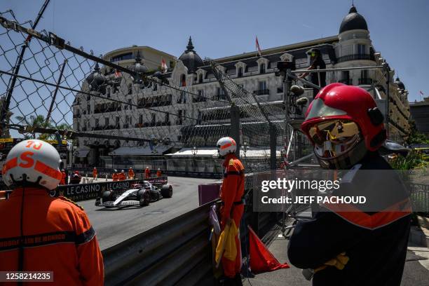 Race marshals stand beside the track as Alpha Tauri's Dutch driver Nyck de Vries drives during the third practice session of the Formula One Monaco...