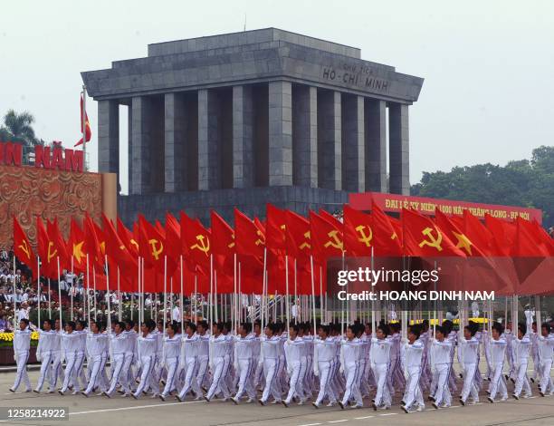 Men holding communist and national flags march in front of the mausoleum of late president Ho Chi Minh during a military parade held on October 10,...
