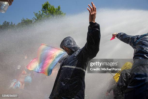 An activist is sprayed by a water cannon while blocking the A12 motorway during an Extinction Rebellion led protest to command an end to all fossil...