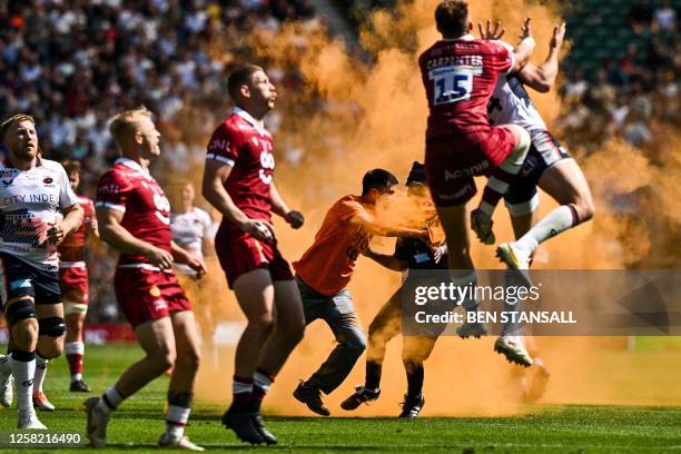 An activist from the environmentalist group "Just Stop Oil" spreads orange powder after entering the pitch as a sign of protest while a security...