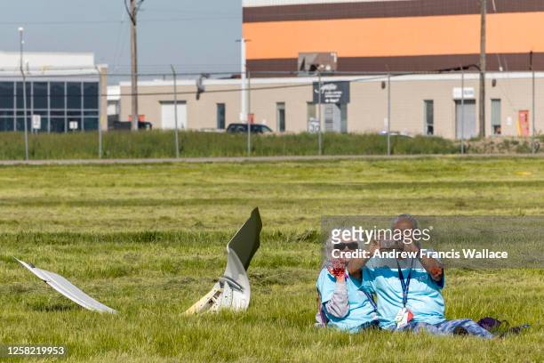 May 27 - Simulated crash victims Susan MacMaster, wearing sunglasses, and Kathleen Douglass wait to be rescued near a placed part of fuselage during...
