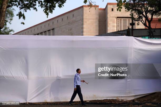 Security guard walks past the covered site of the new parliament building ahead of its inauguration in New Delhi, India on May 27, 2023.