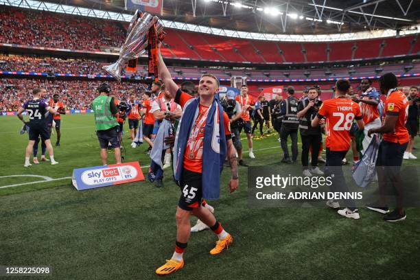 Luton Town's English midfielder Alfie Doughty celebrates on the pitch with the trophy after Luton win the penalty shoot-out in the English...