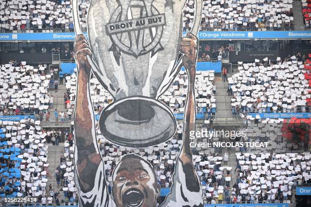 Marseille supporters brandish tifo in their team colours and a giant banner banner depicting former player Basile Boli holding the Champions League...