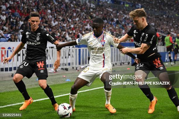 Reims' French forward Alexis Flips and Reims' Belgian midfielder Thomas Foket fight for the ball with Lyon's French defender Sael Kumbedi during the...