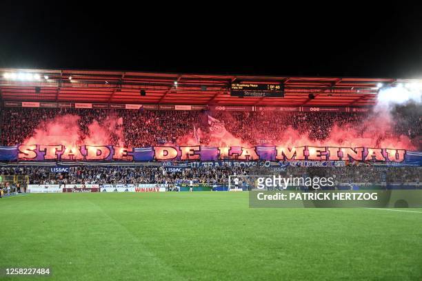 Strasbourg's supporters display a giant banner and light flares at the end of the French L1 football match between RC Strasbourg Alsace and Paris...
