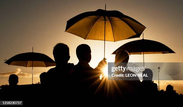 Priests are sheltered by umbrellas during Holy Communion as Pope Benedict XVI presides over a Celebration of Mass in Bellahouston Park, Glasgow, in...