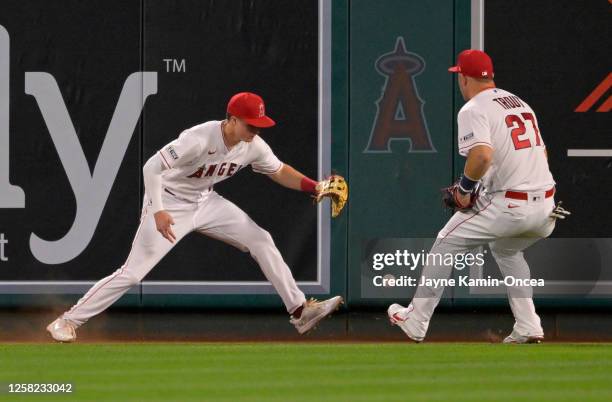 Mickey Moniak and Mike Trout of the Los Angeles Angels scramble to field a two RBI double hit by Garrett Cooper of the Miami Marlins in the tenth...